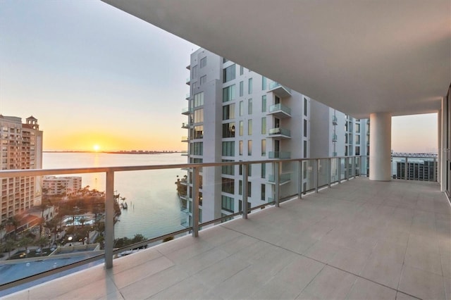 balcony at dusk featuring a water view