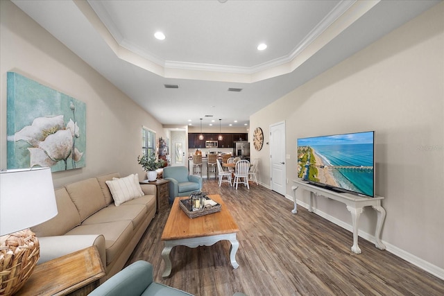 living room with hardwood / wood-style flooring, a tray ceiling, and crown molding