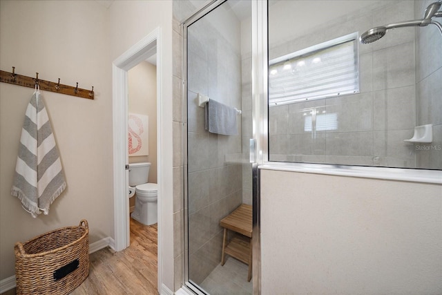 bathroom with hardwood / wood-style flooring, toilet, and a shower with door