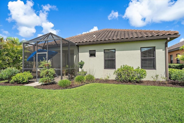 rear view of property featuring glass enclosure and a lawn