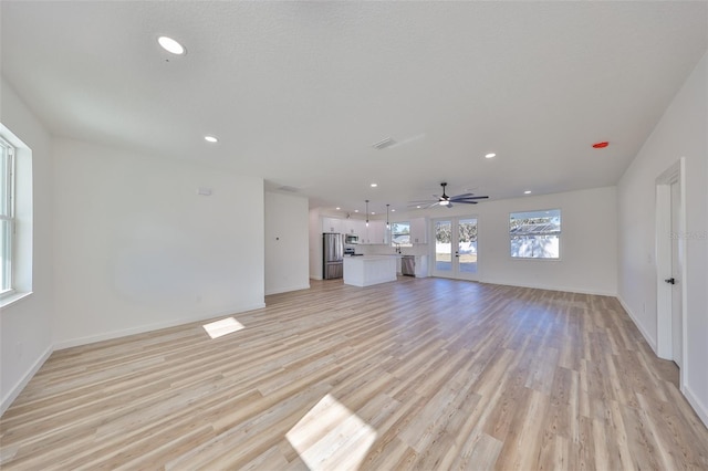 unfurnished living room with french doors, ceiling fan, and light wood-type flooring