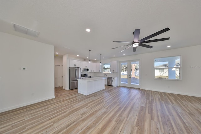 kitchen featuring appliances with stainless steel finishes, white cabinets, hanging light fixtures, a center island, and french doors