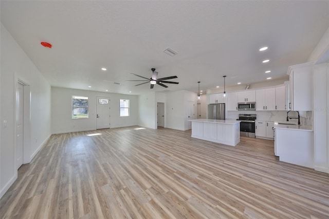 kitchen featuring pendant lighting, sink, appliances with stainless steel finishes, white cabinetry, and a center island