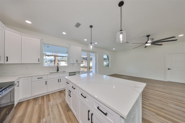 kitchen featuring stainless steel appliances, white cabinetry, a kitchen island, and sink