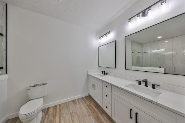 bathroom with toilet, a shower, wood-type flooring, a textured ceiling, and vanity