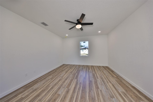 empty room with ceiling fan, light hardwood / wood-style flooring, and a textured ceiling