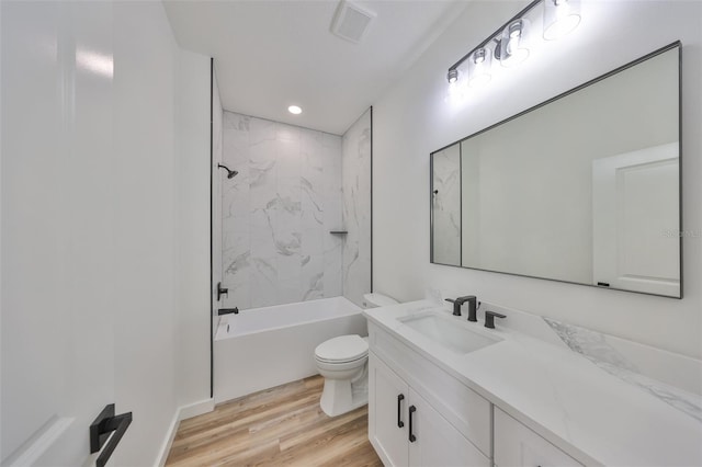 full bathroom featuring hardwood / wood-style flooring, tiled shower / bath, vanity, and toilet