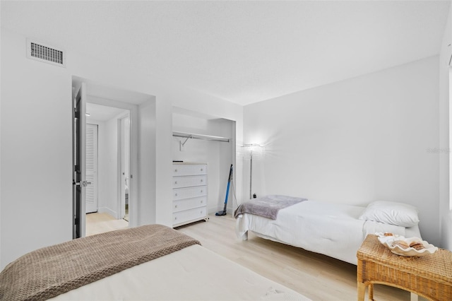 bedroom with light wood-type flooring and a closet