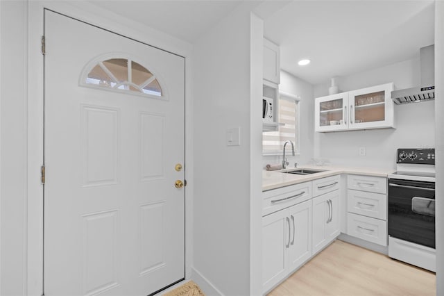 kitchen with white cabinets, wall chimney range hood, sink, and electric range