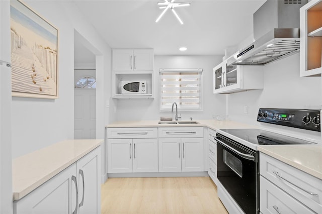 kitchen with range with electric stovetop, sink, white cabinets, light hardwood / wood-style floors, and wall chimney range hood