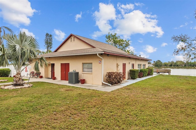 back of property with central AC unit, a lawn, a patio, and a water view