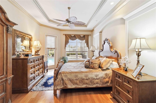 bedroom featuring ornamental molding, access to exterior, a raised ceiling, and light wood-type flooring