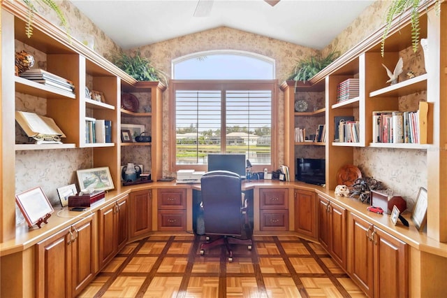 unfurnished office featuring lofted ceiling, built in desk, and light parquet floors