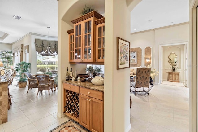 bar with hanging light fixtures, light tile patterned floors, a notable chandelier, light stone counters, and crown molding