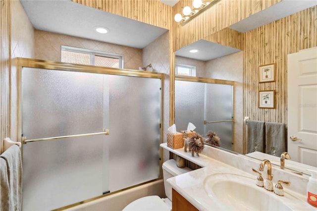 full bathroom with vanity, plenty of natural light, shower / bath combination with glass door, and toilet