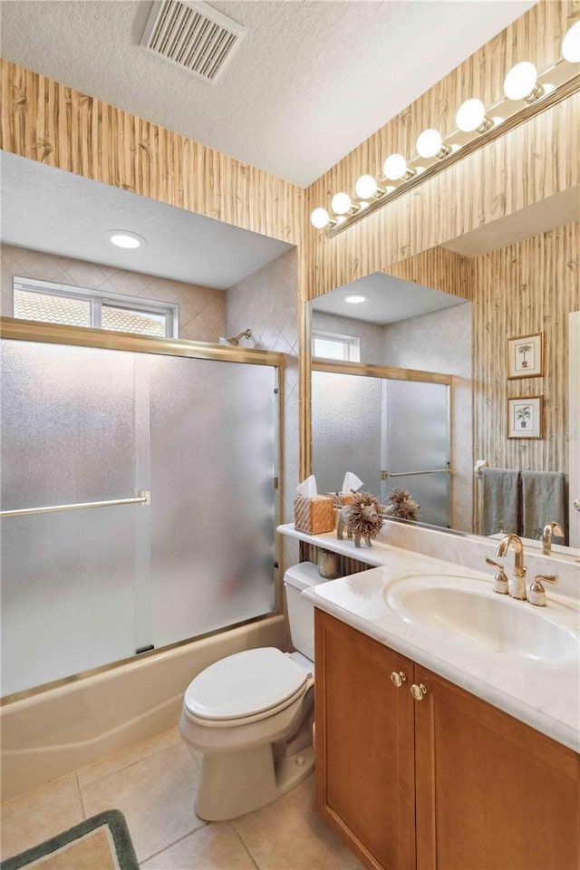 full bathroom with tile patterned floors, bath / shower combo with glass door, a textured ceiling, and vanity