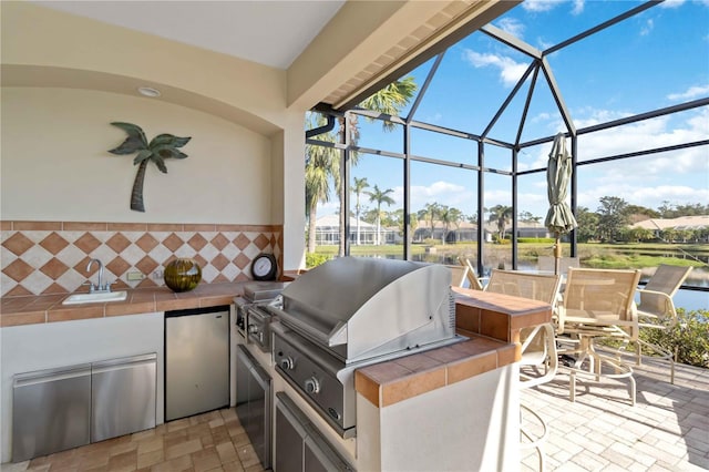 view of patio / terrace featuring an outdoor kitchen, a grill, sink, and glass enclosure