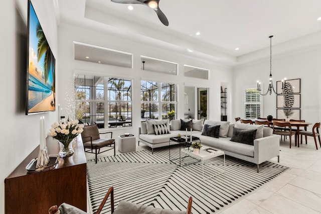 living room featuring a towering ceiling, a tray ceiling, and ceiling fan with notable chandelier