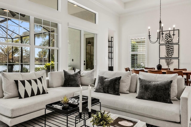 living room featuring ornamental molding, a water view, a towering ceiling, and a notable chandelier