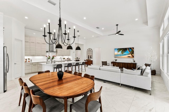 dining area featuring a tray ceiling, sink, ceiling fan, and a towering ceiling