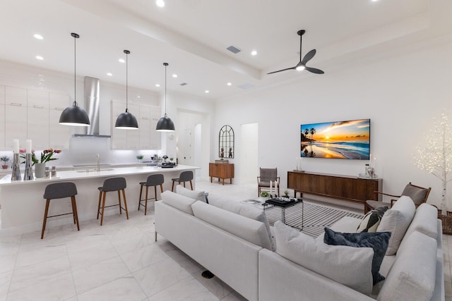 living room featuring a high ceiling, sink, and ceiling fan