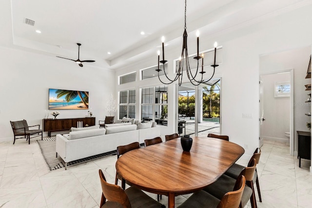 dining area featuring a tray ceiling, ceiling fan with notable chandelier, and a high ceiling