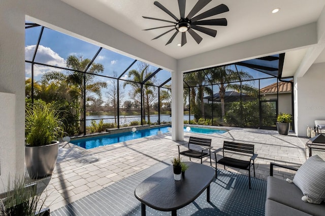 view of pool featuring a water view, ceiling fan, a patio area, and glass enclosure