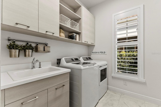 clothes washing area featuring sink, washing machine and dryer, and cabinets