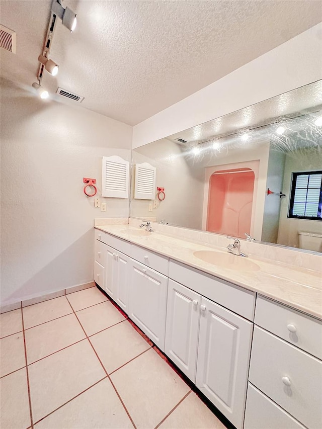 bathroom with tile patterned floors, toilet, a textured ceiling, track lighting, and vanity