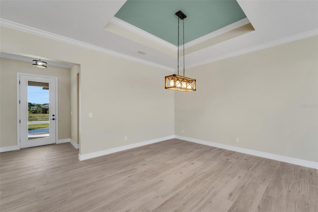 unfurnished room featuring ornamental molding, a tray ceiling, and light wood-type flooring