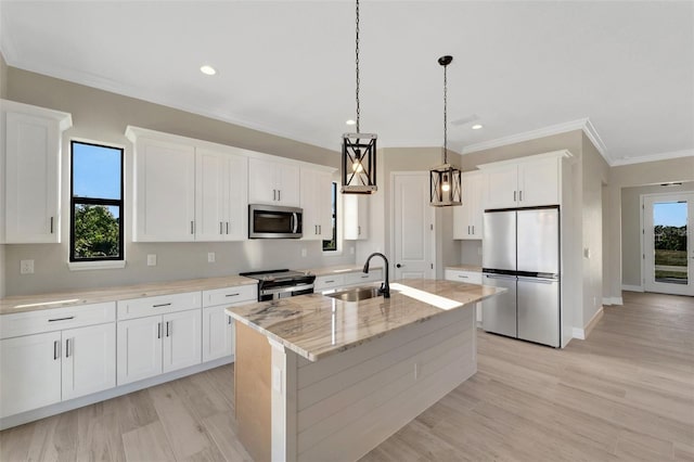 kitchen featuring appliances with stainless steel finishes, pendant lighting, sink, white cabinets, and a kitchen island with sink