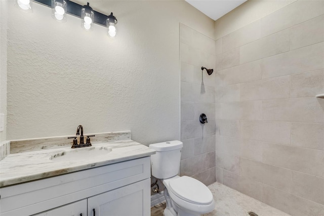 bathroom featuring vanity, toilet, and tiled shower