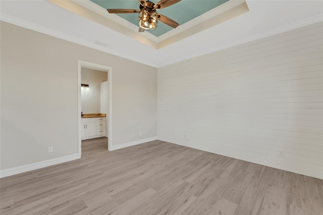 unfurnished room with crown molding, light hardwood / wood-style flooring, a raised ceiling, and ceiling fan