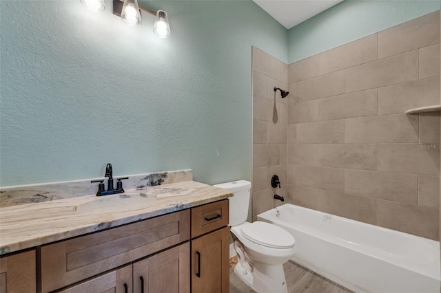 full bathroom with tiled shower / bath combo, vanity, hardwood / wood-style floors, and toilet