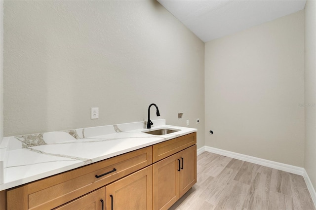 washroom with sink, cabinets, hookup for a washing machine, hookup for an electric dryer, and light wood-type flooring