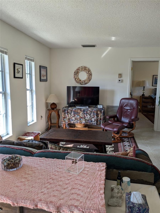 living room with a textured ceiling and light tile patterned flooring