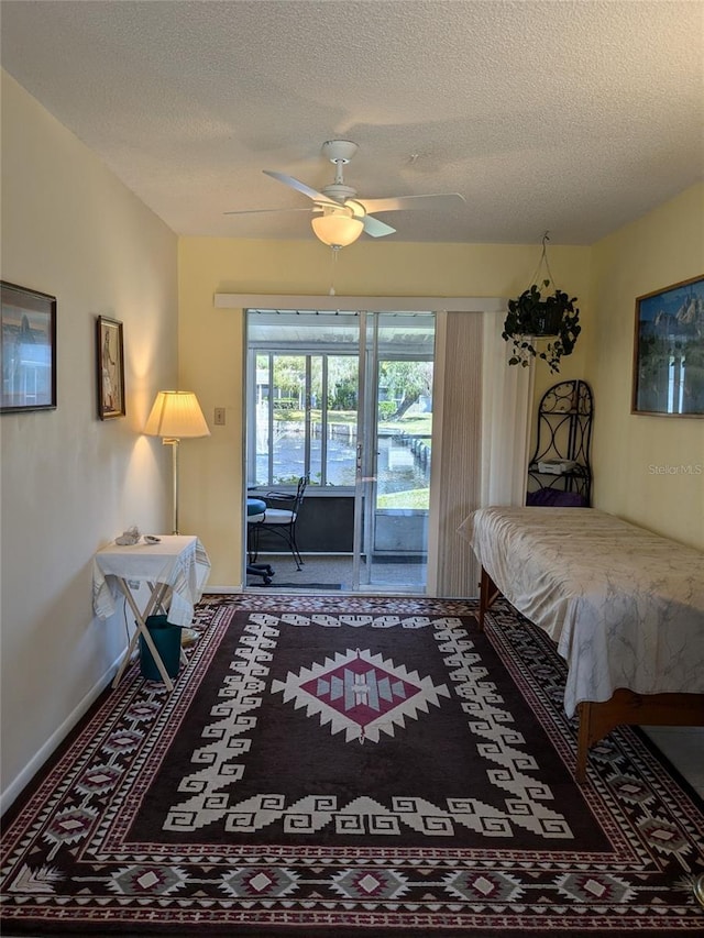 bedroom with ceiling fan, carpet flooring, access to exterior, and a textured ceiling