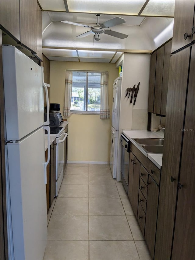 kitchen featuring sink, white appliances, light tile patterned floors, ceiling fan, and stacked washer and clothes dryer