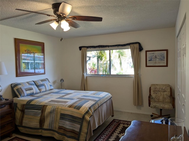 tiled bedroom featuring ceiling fan, a closet, and a textured ceiling