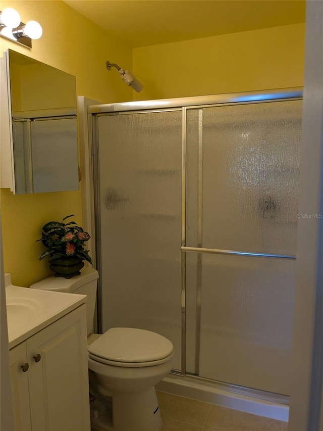 bathroom featuring vanity, an enclosed shower, tile patterned floors, and toilet