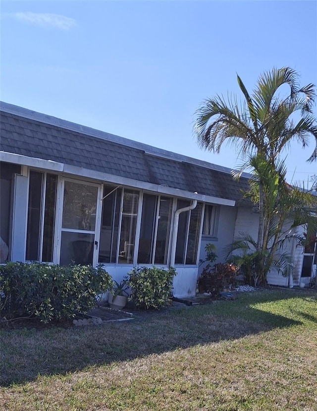 view of home's exterior featuring a sunroom and a lawn