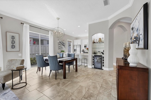 dining space featuring crown molding, a textured ceiling, wine cooler, and an inviting chandelier