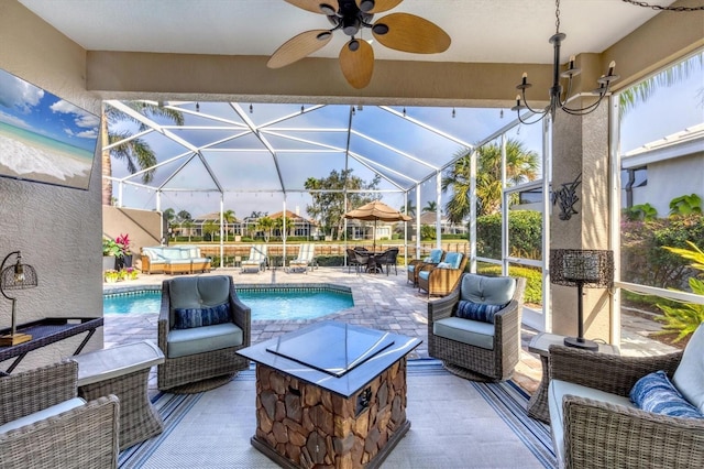 view of patio with ceiling fan, an outdoor hangout area, and glass enclosure