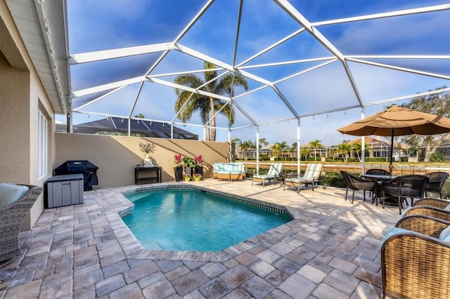 view of pool featuring a grill, a patio area, and glass enclosure