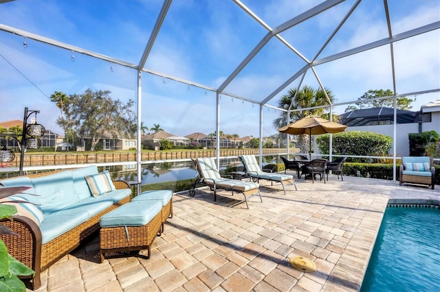 view of patio / terrace featuring a water view, an outdoor living space, and glass enclosure