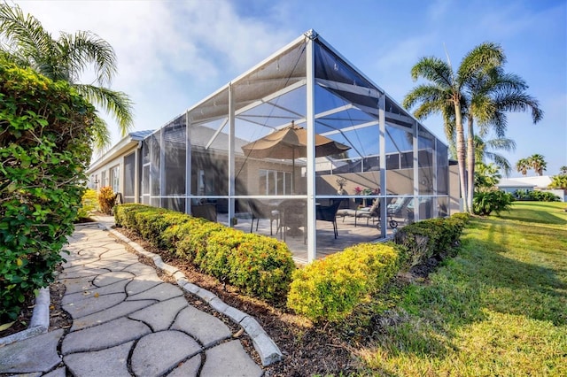 rear view of house with a lanai, a lawn, and a patio