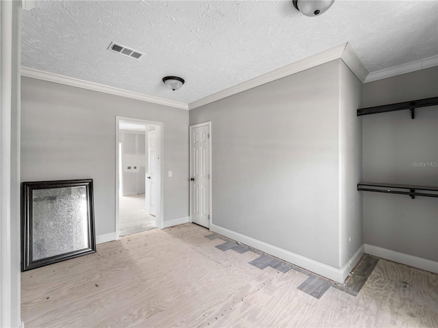 unfurnished bedroom featuring ornamental molding, a textured ceiling, light wood-type flooring, and a closet