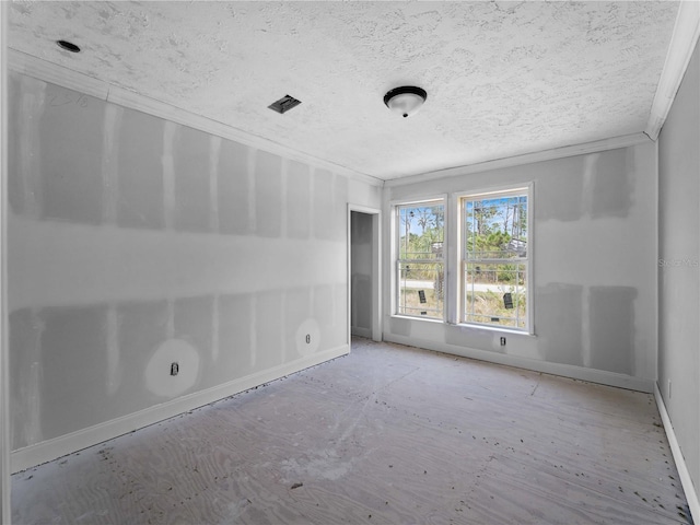 unfurnished room featuring ornamental molding and a textured ceiling