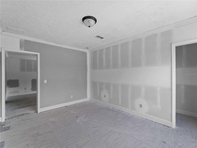 spare room featuring crown molding and a textured ceiling