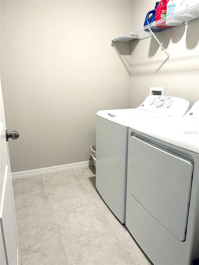 clothes washing area with washing machine and dryer and light tile patterned floors